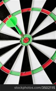 Green dart punctured in the center of the target