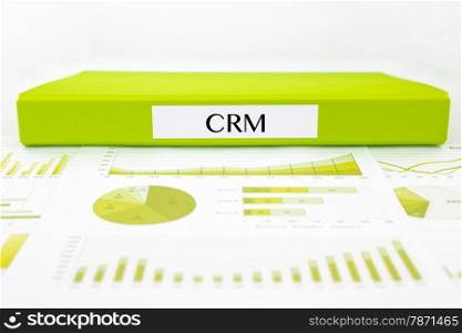Green document binder with CRM customer relationship management word place on graph analysis and business reports