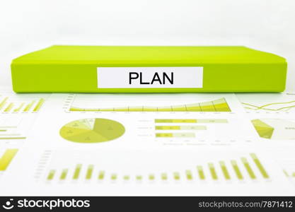 Green document binder with PLAN word place on graphs and charts of data analysis, strategic plan management concept