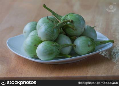 green eggplants in the plate on wooden table