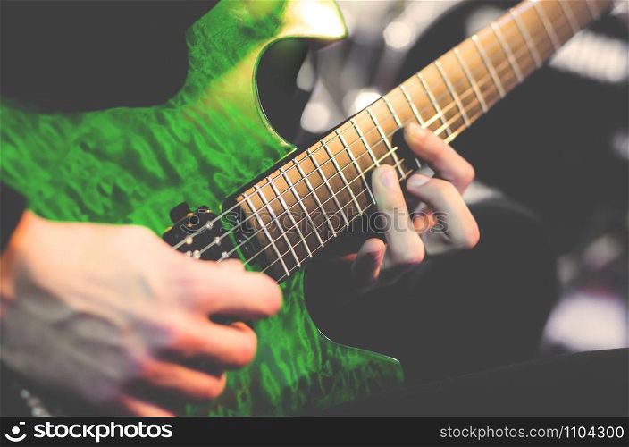 Green electric guitar and guitar player's hands. Guitar fretboard