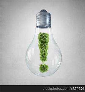 Green energy concept. Glass light bulb with green exclamation mark inside
