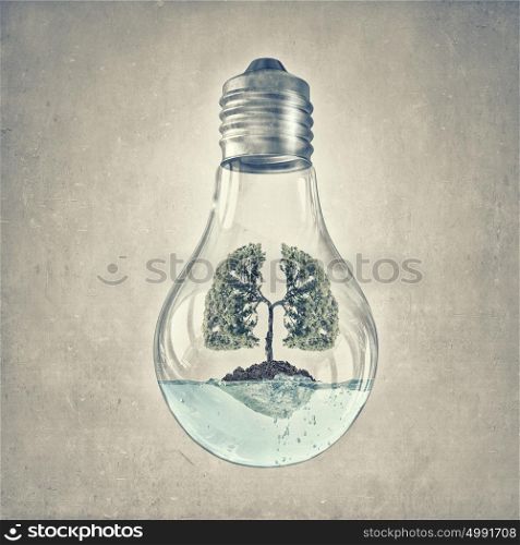 Green energy concept. Glass lightbulb with green tree growing inside