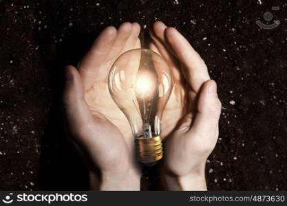 Green energy concept. Hand holding eco light bulb energy concept and soil at background