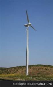 Green energy generating wind turbine in a blue sky