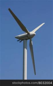 Green energy generating wind turbine in a blue sky