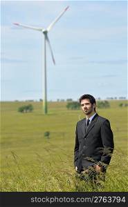 Green energy - Young businessman in field windmill in background