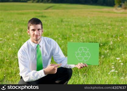 Green energy - Young businessman in sunny meadows hold recycling sign