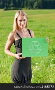 Green energy - Young businesswoman in sunny meadows hold recycling sign