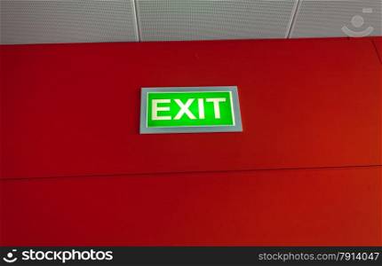 Green exit sign glowing on red wall