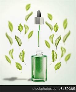 Green facial Serum or oil bottle with pipette and green leaves. Modern skin care and beauty natural cosmetic concept