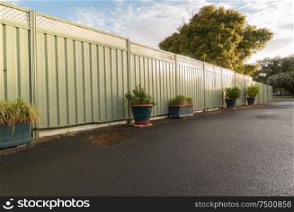 Green fence and wet asphalt road on garden