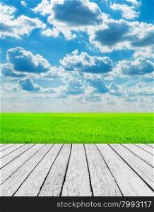 Green field under blue sky. Wood planks floor. Beauty nature background