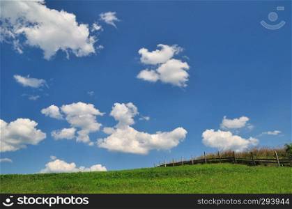 Green field with clouds on blue sky