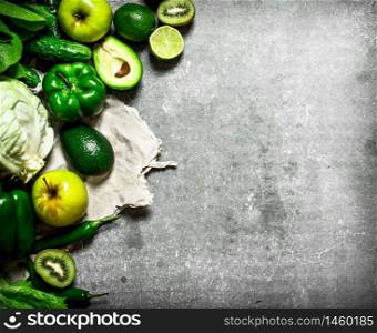 Green food. Green fruits and vegetables. On the stone table.. Green fruits and vegetables.