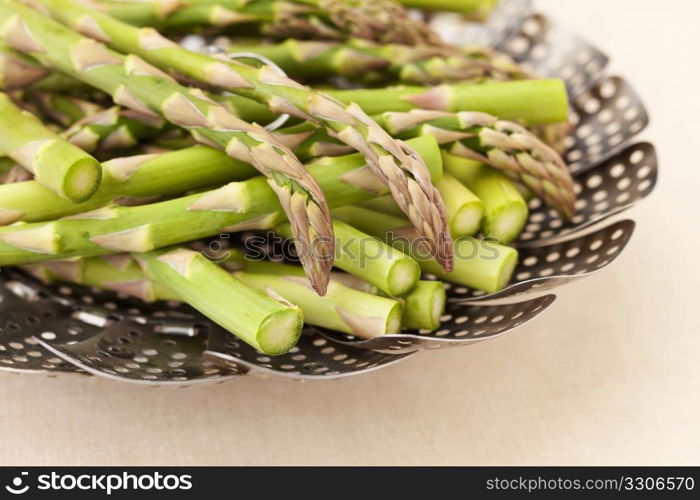 green fresh asparagus in a steamer basket ready for steaming