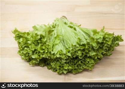 Green fresh bunch of a lettuce on a wooden background . The best healthy breakfast for the modern person.. Green fresh bunch of a lettuce on a wooden background . The best healthy breakfast for the modern person