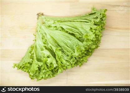 Green fresh bunch of a lettuce on a wooden background . The best healthy breakfast for the modern person.. Green fresh bunch of a lettuce on a wooden background . The best healthy breakfast for the modern person
