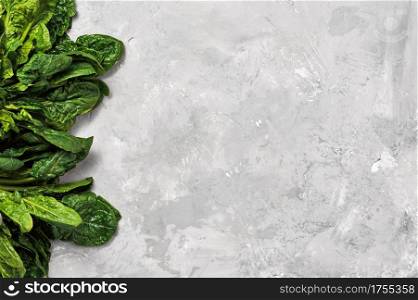 Green fresh spinach leaves on a neutral gray background. Top view with copy space for text. Healthy detoxification vegan diet concept