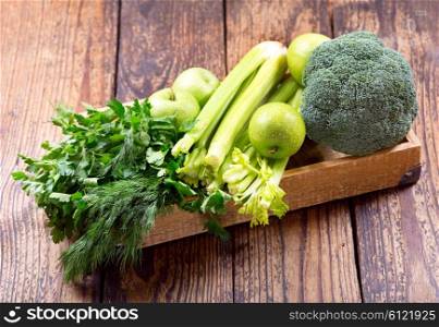 green fruit and vegetables in a n box on wooden table