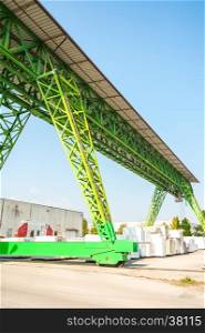 Green gantry crane at work in a warehouse of marble blocks