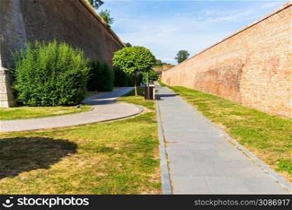Green garden with clean grass, beautiful trees, alleys in a fortress yard. The fortification walls and promenades in Alba Iulia, Romania, 2021