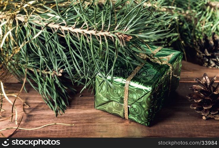 Green gift box under Christmas tree branches. Green gift box under Christmas tree branches. Wrapped in green paper gift box Toned image