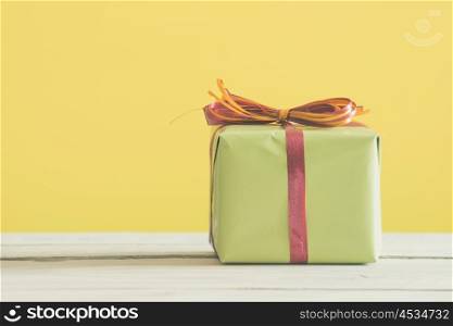 Green gift with a red and orange ribbon on a table