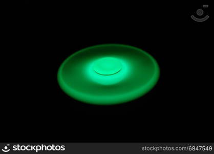 Green glowing in the dark fidget spinner spinning on black background. Glowing in the dark fidget spinner, rotating