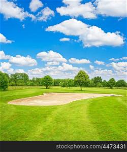 Green golf course field and blue cloudy sky. European nature landscape