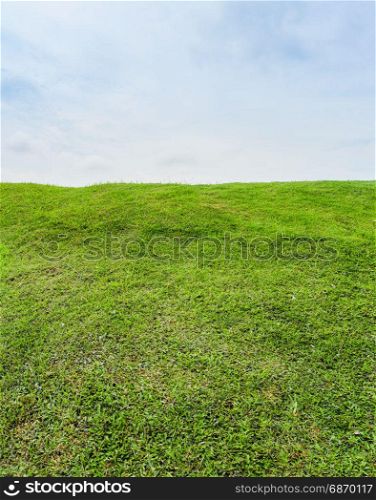 Green grass field on small hill and blue sky with clouds, beautiful green hills springtime