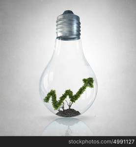 Green growing graph. Green plant shaped like graph inside glass light bulb