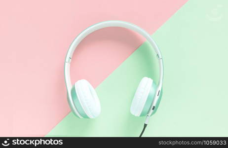 Green headphone and black cable isolated on a green and pink background pastel.