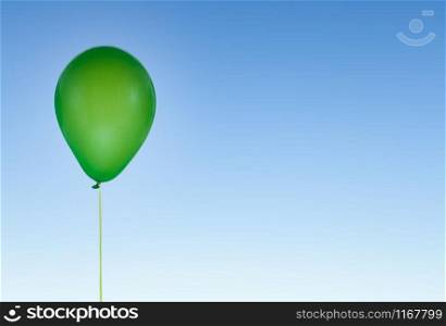Green helium party balloon for birthday and celebrations isolated at blue sky with copy space for free text. Green balloon for birthday and celebrations isolated at blue sky