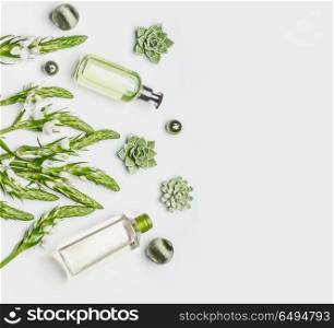 Green herbal natural cosmetic setting with bottles of facial cleansing products, herbs and flowers on white background , top view, flat lay. Beauty and skin care concept