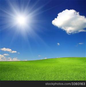 green hill with wheat under blue sky with sun