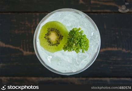 Green Italian Soda Cold Beverage and Kiwi Fruit and Parsley. Green Italian Soda Cold Beverage with Kiwi fruit and ice in glass on wood table. Green Italian Soda with Kiwi for food and drink category