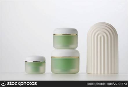 green jar for cosmetics on a white table. Packaging for cream, gel, serum, advertising and product promotion, mock up