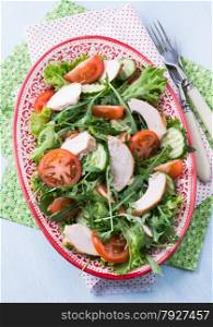 Green leaf salad with vegetables and chicken, top view