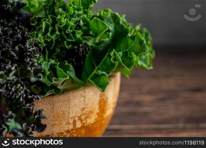 green leafy kale vegetable in bamboo bowl on wooden table background. green leafy kale