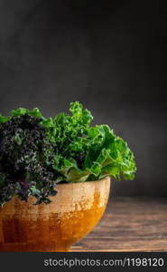 green leafy kale vegetable in bamboo bowl on wooden table background. green leafy kale