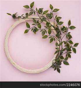 green leaves decorated wooden empty circle frame against pink backdrop