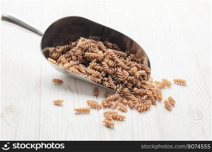 Green lentil fusilli pasta on a wooden background. A scoop of raw pasta and green lentils. Gluten-free pasta.