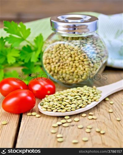Green lentils in a glass jar and a wooden spoon, parsley, tomatoes, doily on a wooden boards background