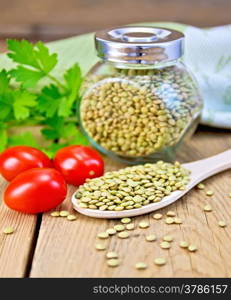 Green lentils in a glass jar and a wooden spoon, parsley, tomatoes, doily on a wooden boards background