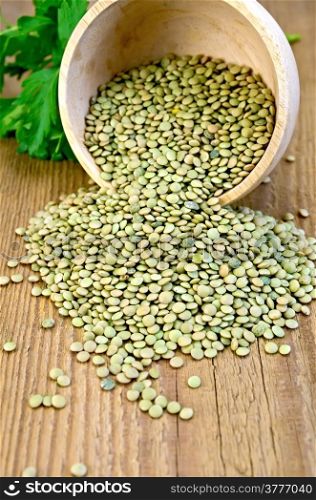 Green lentils in a wooden bowl with parsley on a wooden boards background