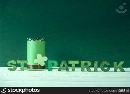 Green leprechaun paper hat with a shamrock and the words St Patrick written in green wooden letters, on a wooden background with space for text.