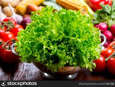 green lettuce salad in colander with fresh vegetables