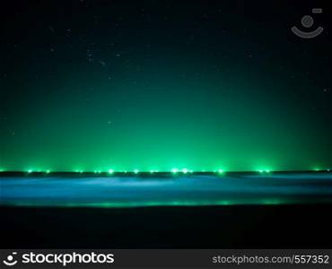 Green light at horizon line over the sea, light from fishing boat, star on the sky and soft movement of wave, Thailand