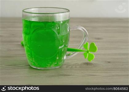 Green liquid in a beer mug displayed with a four leaf clover for St. Patrick's day